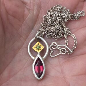 Balancing act necklace; 12x5mm rhodolite garnet, unheated sapphire, silver and 24ct gold. Length 46.5cm